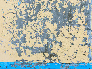 Peeling paint on the wall. Old concrete wall with cracked flaking paint. Weathered rough painted surface with patterns of cracks and peeling. Grunge texture for background and design. High resolution.