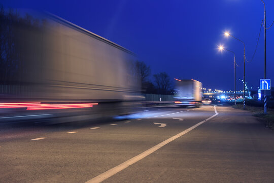 Trucks drive at night along the highway into the city.