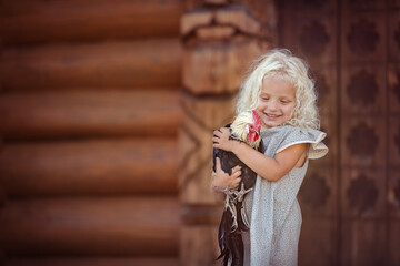 Girl with blonde hair with chicks near wooden house in countryside  © Olga