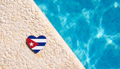Cuba flag in the shape of a heart near the pool in the hotel. Holiday concept in Cuban hotels