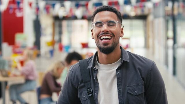 Portrait Of Smiling Male University Student Wearing Glasses Standing Inside College Building