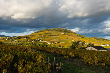 Mont Brouilly, couvert de vignes du Beaujolais colorées par l’automne, sous les nuages mais...