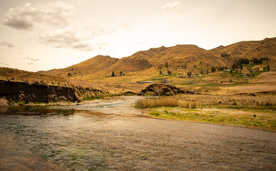 Nearby river with scenic landscape in the background and distant mountains, cloudy sky in Langui, Cusco, Peru.