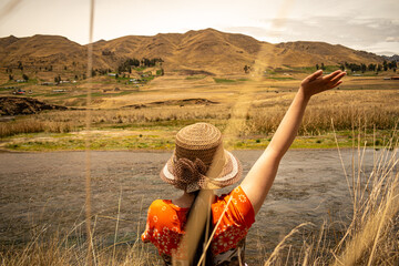young woman with hat in the foreground enjoying the landscape, nearby river, distant mountains and...