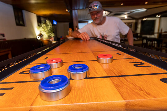 Man playing a focused game of shuffleboard