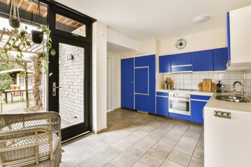 Blue kitchen with cabinets and appliances by bright window