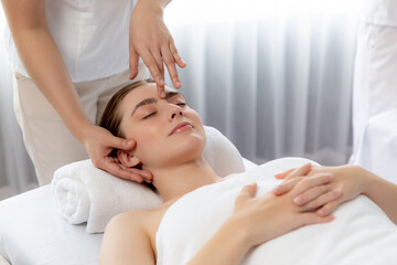 Fototapeta na wymiar Caucasian woman enjoying relaxing anti-stress head massage and pampering facial beauty skin recreation leisure in dayspa modern light ambient at luxury resort or hotel spa salon. Quiescent