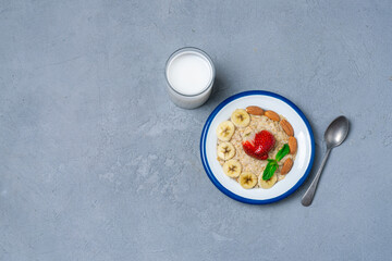 Oatmeal with banana slices, almonds and strawberries. Oatmeal with fruit and milk. Healthy breakfast. Healthy eating. View from above.