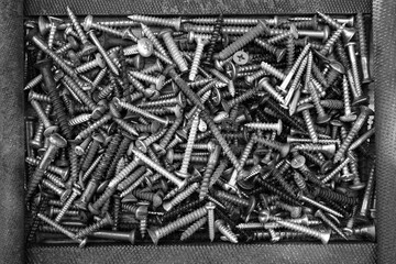 Metal steel gray bolts, nuts, screws and screws are lying on the floor. Fasteners and hardware for...