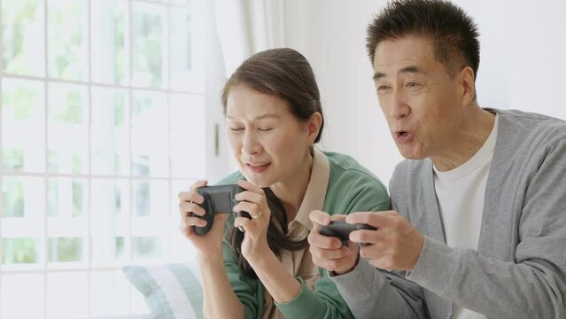 家でゲームをする高齢者夫婦
