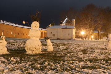 Funny snowmen at night and old castle and church