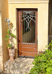 Fototapeta na wymiar Sunny yellow Mediterranean style villa with metalwork on the mahogany front door