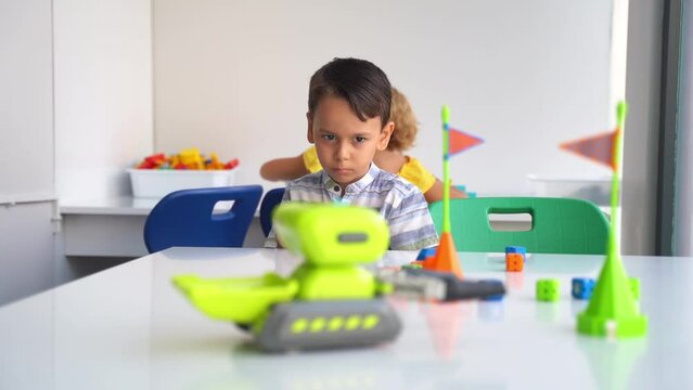 Child boy developing fine motor skills playing with electronic remote toy car control panel in technological educational class using joystick. Preschool kids exploring technology first steps