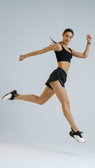 Athletic active woman jumping on studio background. Dynamic movement