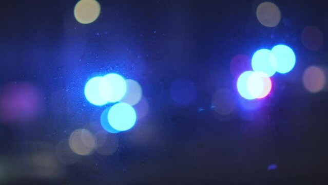 Bokeh effect lights from ambulance car flashing on street outside of window alerting people about emergency. Blinking blue and red cautionary lights