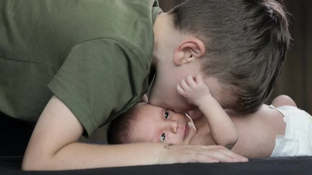 Older brother kisses his newborn brother on the cheek. Happy family. Happy newborn baby with his brother.