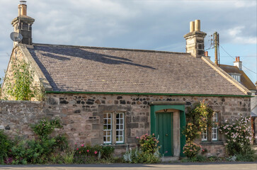 Scottish cottage with roses around the sheltered front door - obrazy, fototapety, plakaty