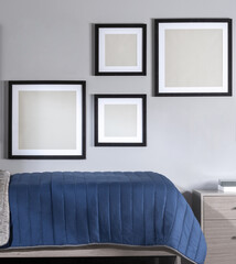 Sleek Bedroom Interior Design, A Collection of Empty Mock-Up Picture Frames Mounted on a Gentle Grey Wall, Luxurious Royal Blue Velvet Bedspread, Contemporary Bed Frame, and Matching Bedside Drawer.