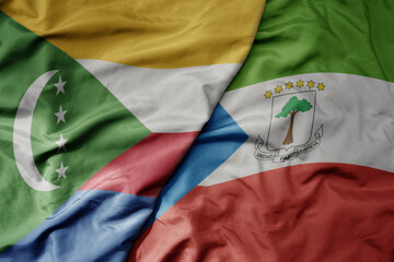 big waving national colorful flag of equatorial guinea and national flag of comoros .