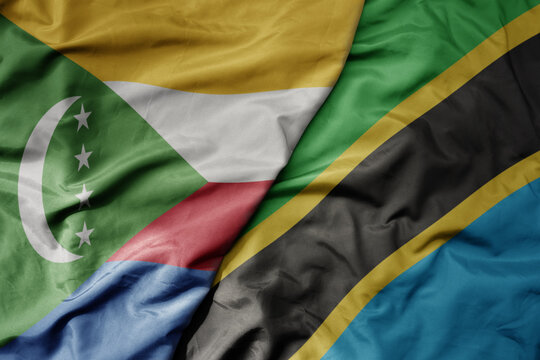 big waving national colorful flag of tanzania and national flag of comoros .