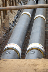 Two large-diameter water pipes in thermal insulation are laid in a trench. Repair, renovation or replacement of municipal equipment in the city. City construction site. Vertical photo