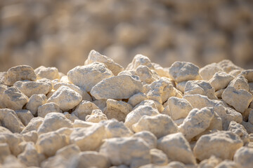 Industrial crushed stone close-up. Bulk material for road construction or laying utilities. Rubble under sunlight and with shadows. Selected focus, filled frame