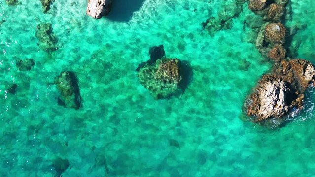Aerial view of rocks at transparent crystal cleat turquoise water