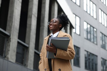 Happy woman with folders outdoors, low angle view. Lawyer, businesswoman, accountant or manager