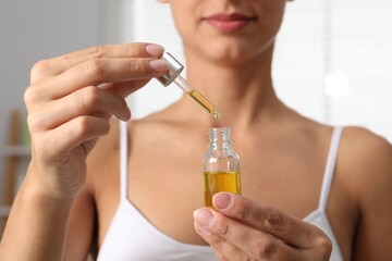 Fototapeta premium Woman with bottle of cosmetic serum on blurred background, closeup