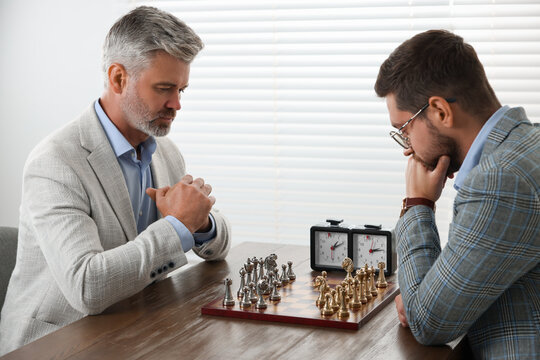 Men playing chess during tournament at table indoors