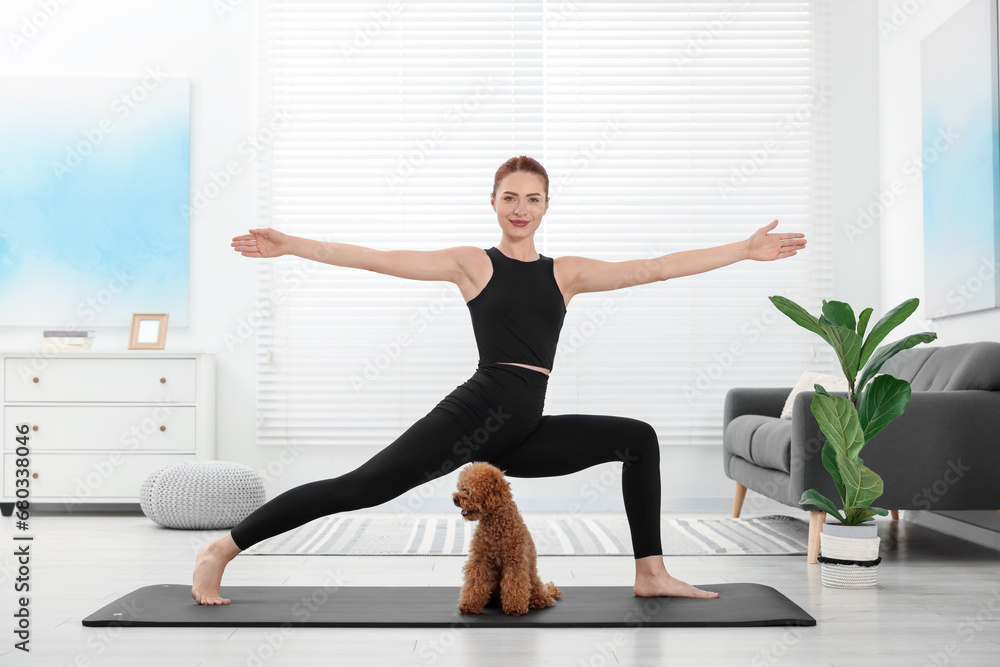 Poster Young woman practicing yoga on mat with her cute dog at home