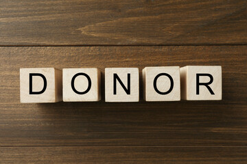 Word Donor made of cubes on wooden table, top view