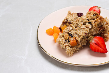 Tasty granola bars and ingredients on light grey marble table, space for text