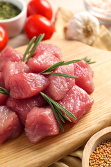 Cooking delicious goulash. Raw beef meat with rosemary on wooden board, closeup