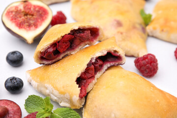 Delicious samosas, berries, mint leaves and fig on white tiled table, closeup