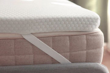 White memory foam mattress topper on grey bed, closeup