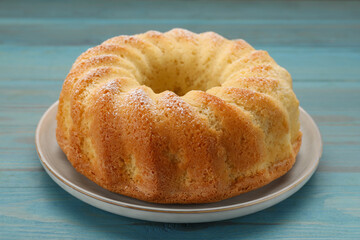 Delicious freshly baked sponge cake on light blue wooden table, closeup
