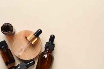 Bottles of cosmetic serum on beige background, flat lay. Space for text