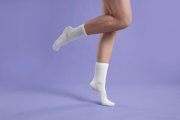 Fototapeta premium Woman in stylish white socks on violet background, closeup