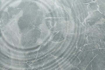 Obraz premium Rippled surface of clear water on light grey textured background, top view