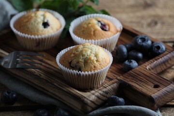 Delicious sweet muffins with blueberries, mint and fork on table, closeup