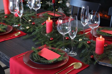 Elegant Christmas table setting with dishware and burning candles in festively decorated room