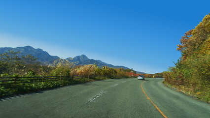 秋の八ヶ岳高原をドライブする車と青空【北杜八ヶ岳公園線】日本山梨県北杜市