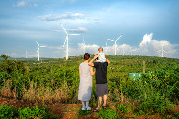 A happy young family looks at wind turbines. Wind turbines are alternative sources of electricity,...