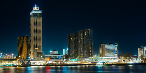 A striking view of the modern high-rise buildings in Rotterdam at night, against a dazzling...