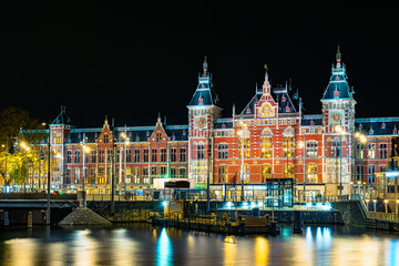 Naklejka premium Long exposure night photograph of Amsterdam Central Station with stunning lighting against a dark sky, showcasing the beauty of the iconic architecture.