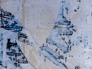 Weathered and torn ads poster glued to cement wall. Abstract grunge background.