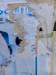 Weathered and torn ads poster glued to cement wall. Abstract grunge background.
