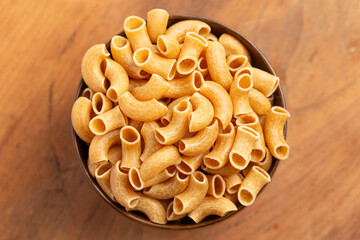 A Bowl of Gluten Free Dry Brown Rice Elbow Macaroni Pasta on a Wooden Table