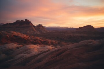 A stunning view of layered canyon formations at sunset, with the warm glow of the setting sun casting a beautiful light over the rugged landscape.

